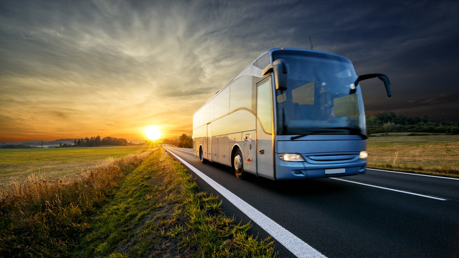Bus fährt vor der Sonne weg, während sie untergeht