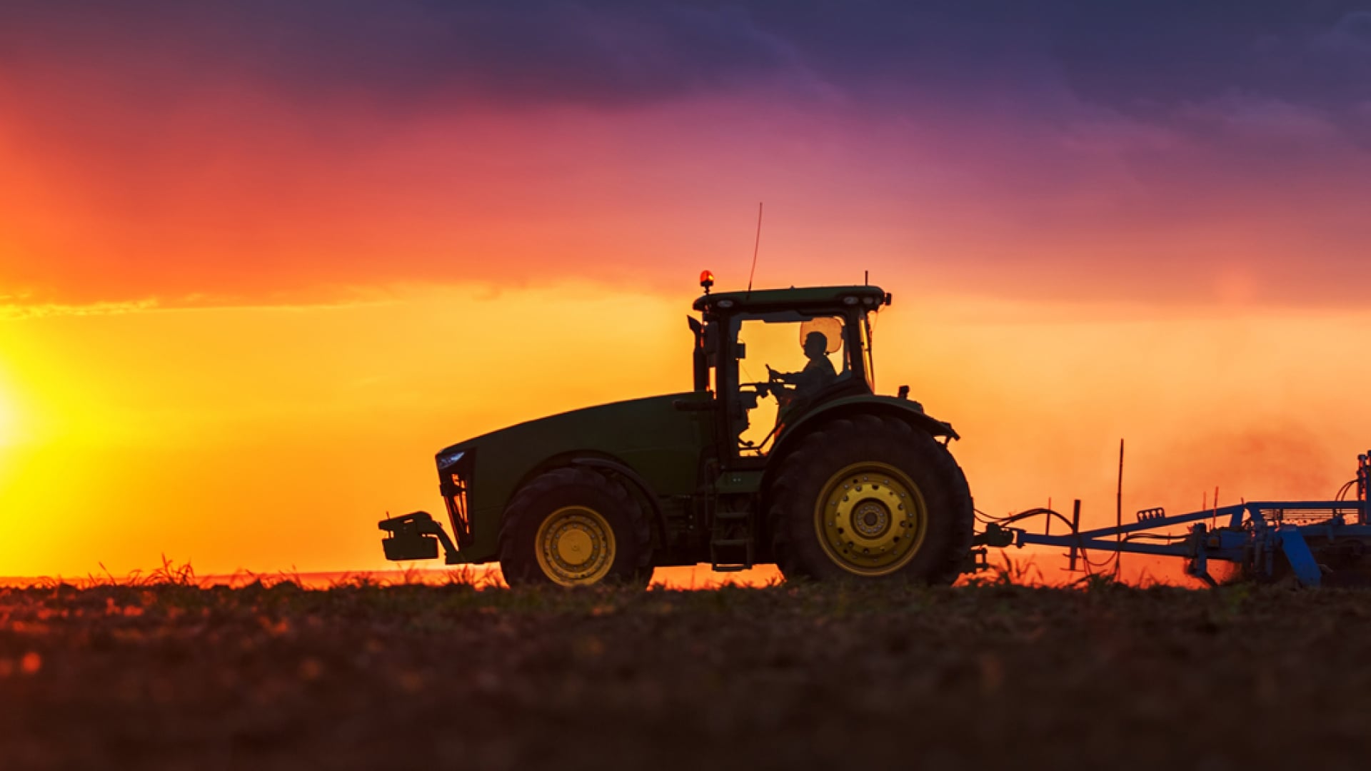 Traktor bei Sonnenuntergang auf einem Feld