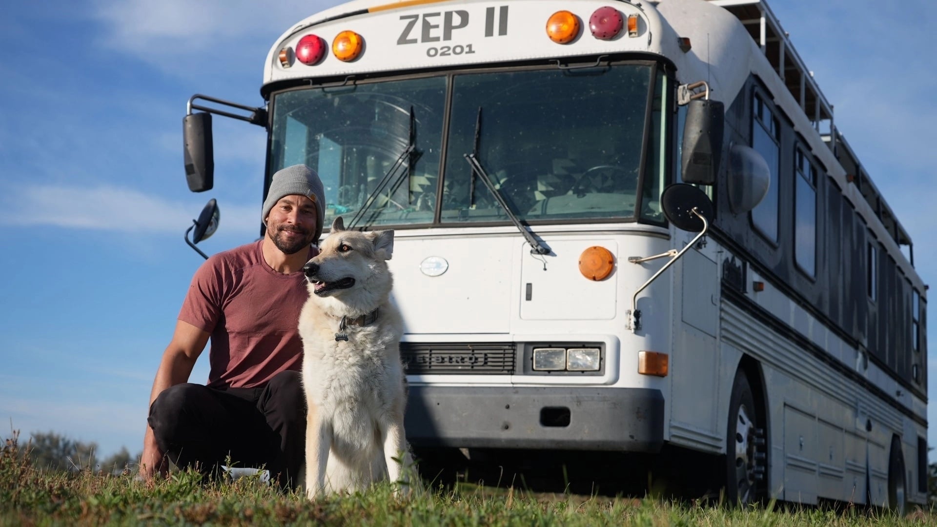 Ein Mann mit seinem Hund vor einem weißen Bus