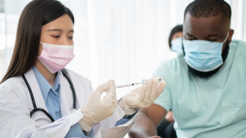Pflegekraft, die einem Patienten eine Spritze verabreicht
