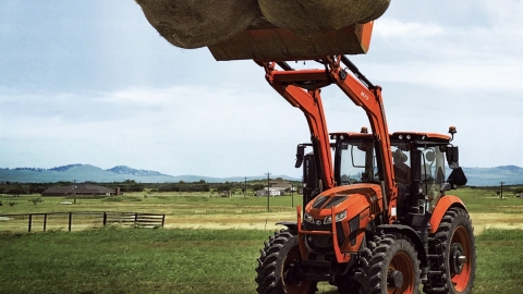 Traktor hebt Heubälle hoch