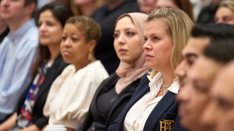 Mitarbeitende sitzen nebeneinander in einer Townhall-Versammlung