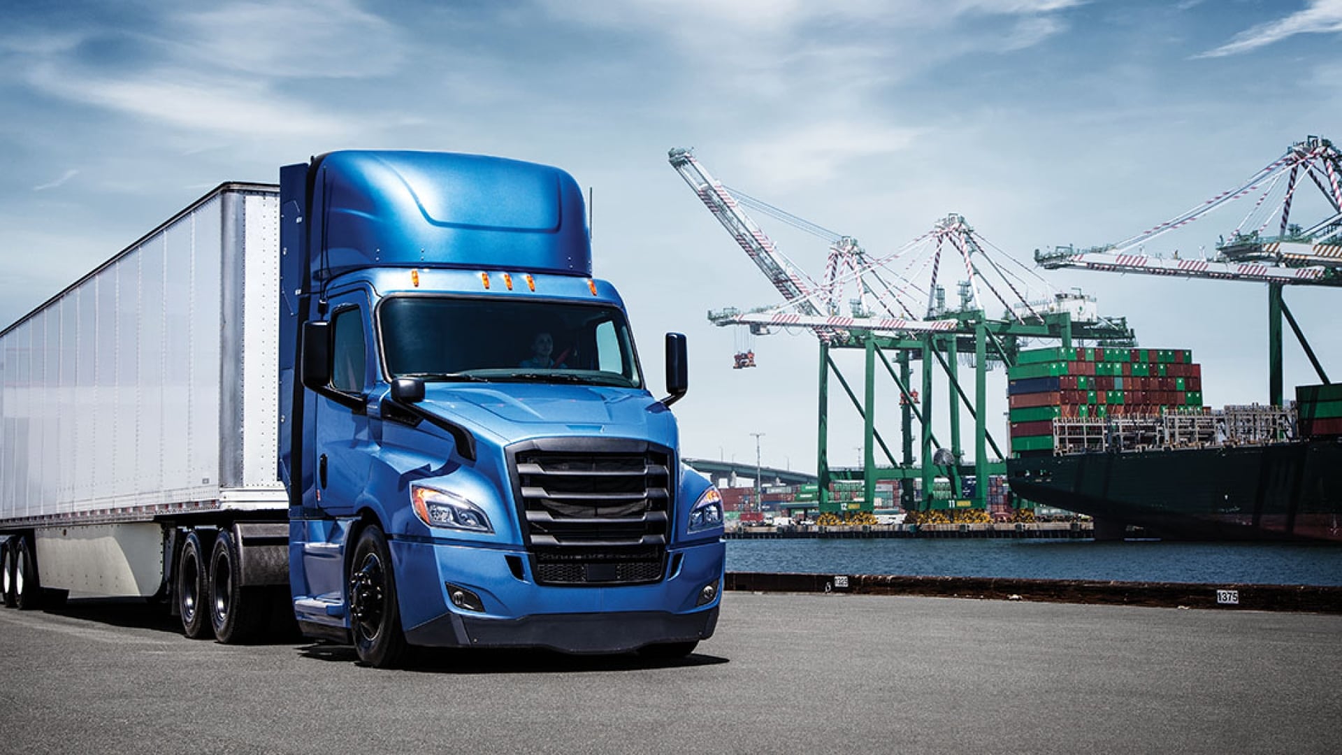 Blauer und weißer Freightliner neben Baumaschinen