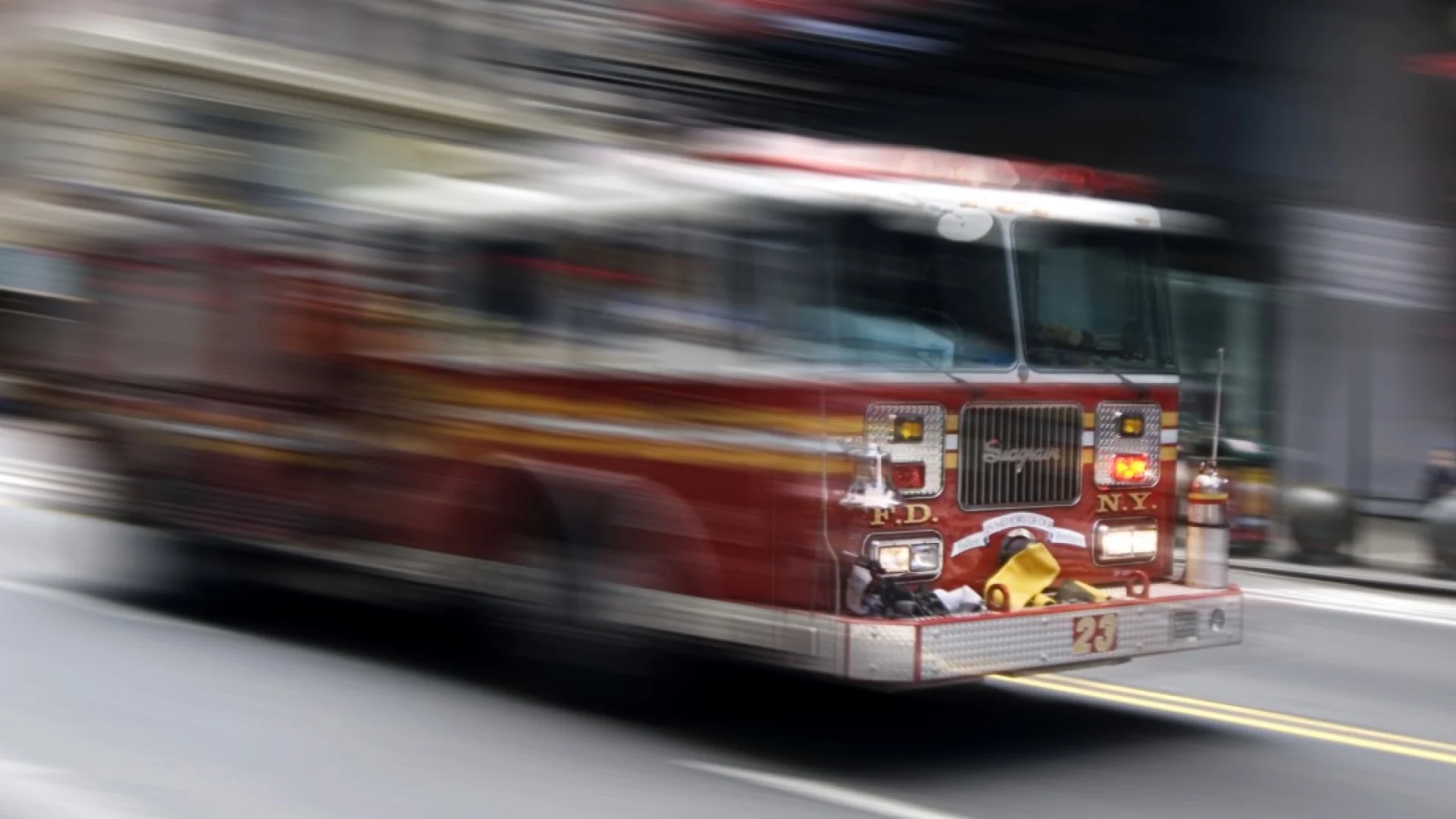 Camión de bomberos rojo a gran velocidad en una calle de la ciudad