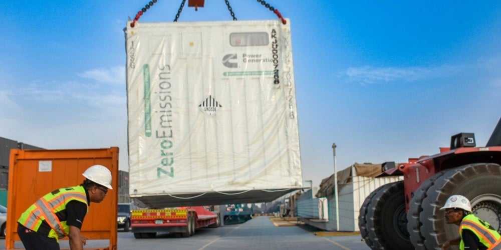 Sistema de almacenamiento de energía de la batería que se levanta con una grúa con 2 personas ayudando.