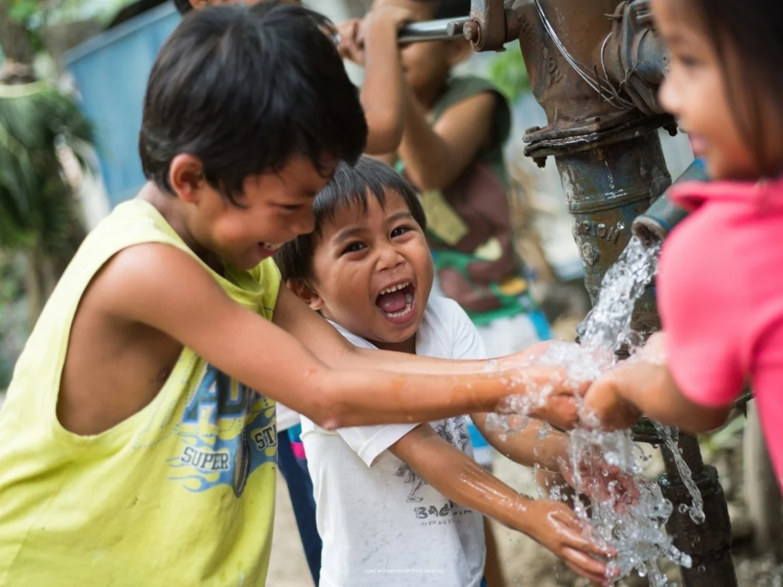 niños alrededor del grifo de agua exterior en Filipinas