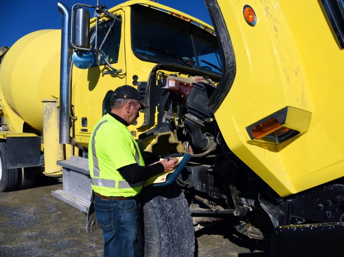 Hombre inspeccionando motor para camión mezclador de concreto
