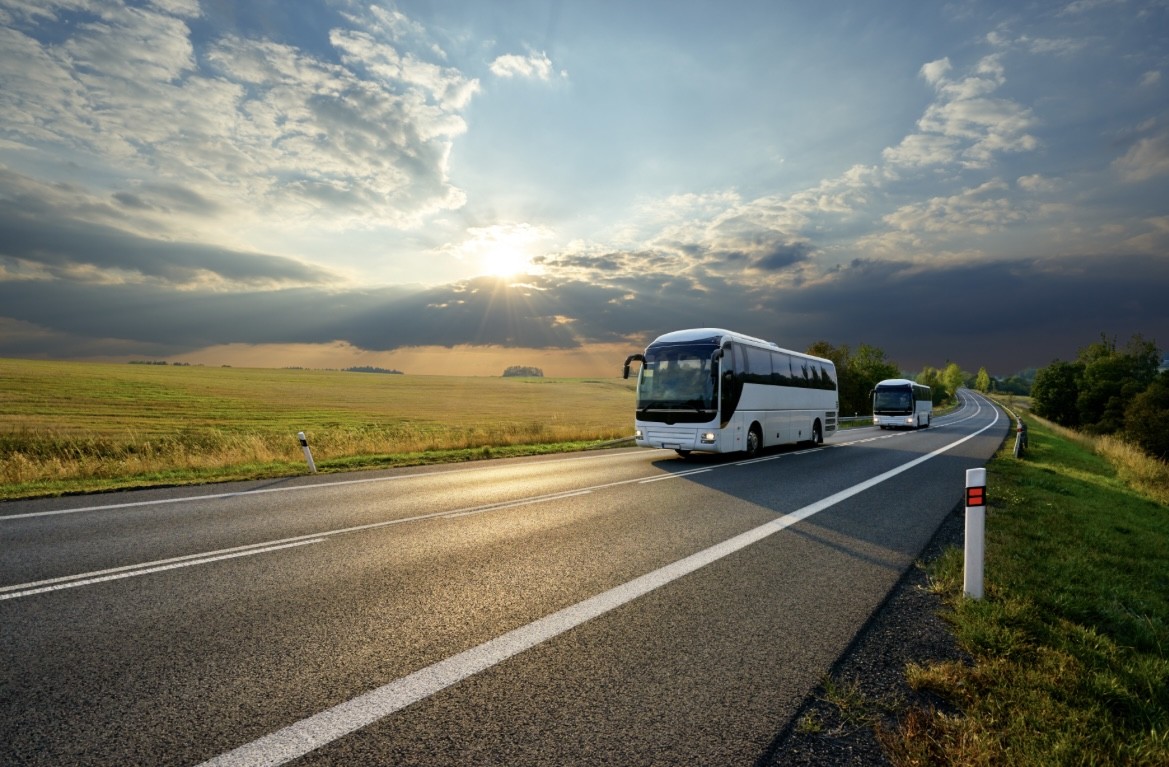 Un bus roulant sur une route plate, avec le soleil en arrière-plan