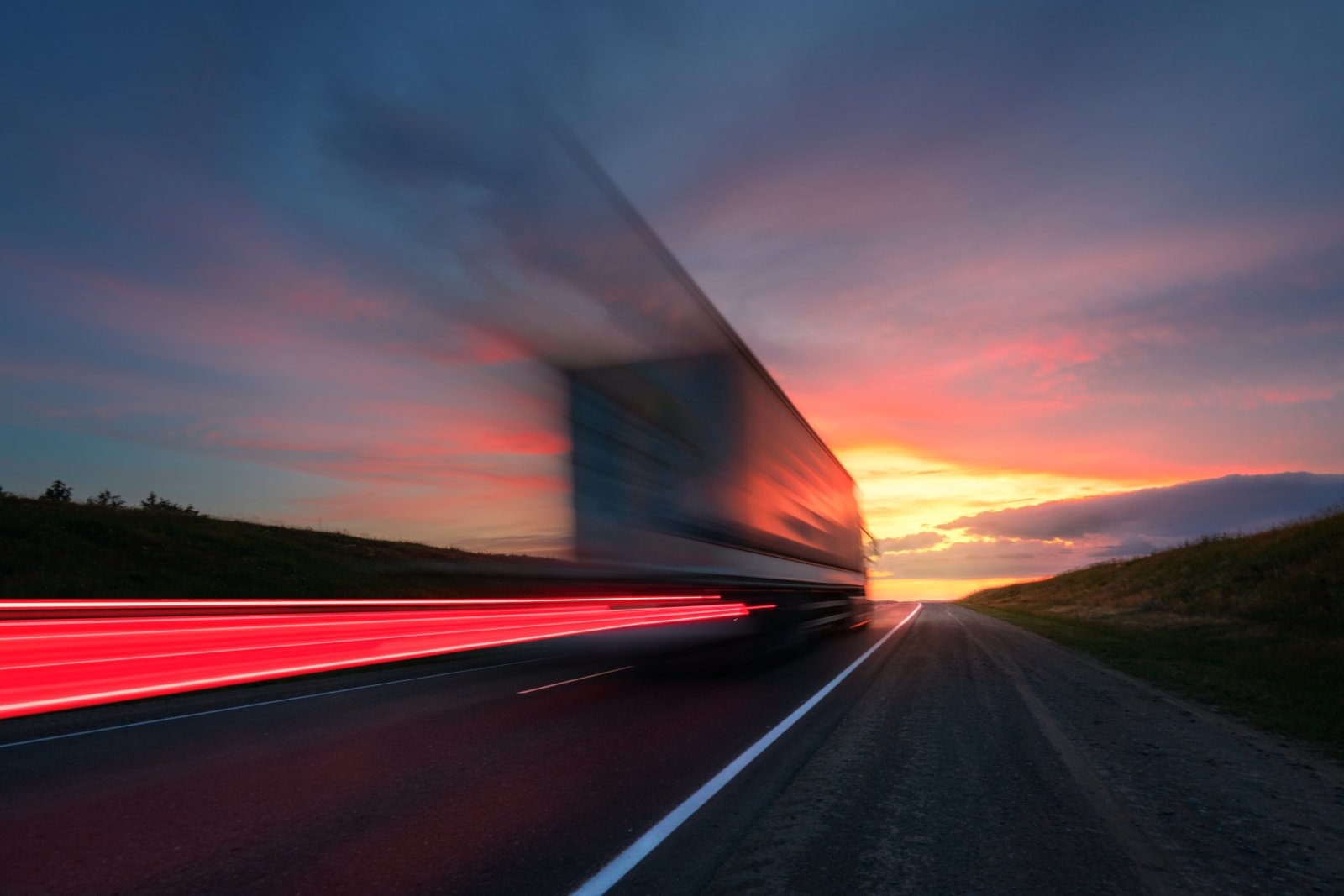 Une longue exposition d’un camion passant au coucher du soleil