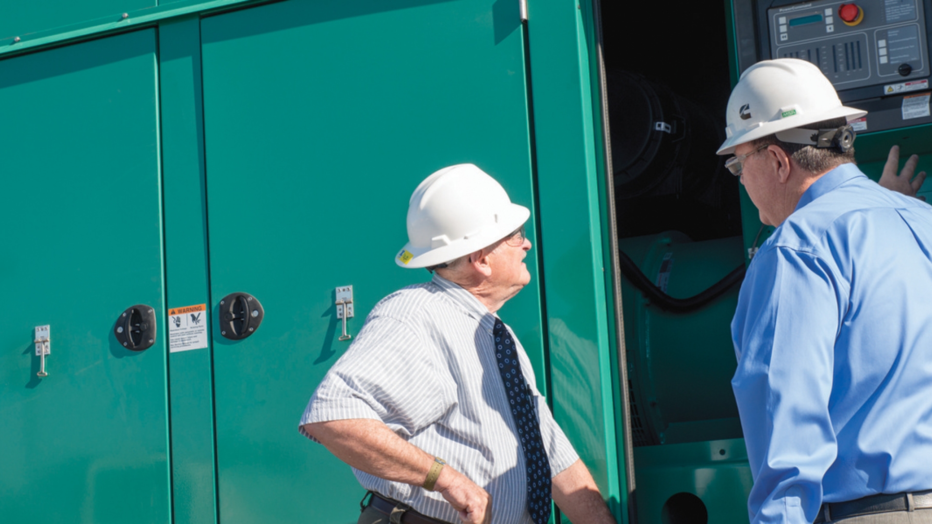 Des hommes discutent à côté du groupe électrogène Cummins.