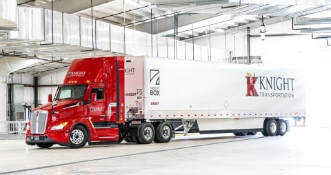 Semi Knight Transportation rouge et blanc garé dans un garage industriel