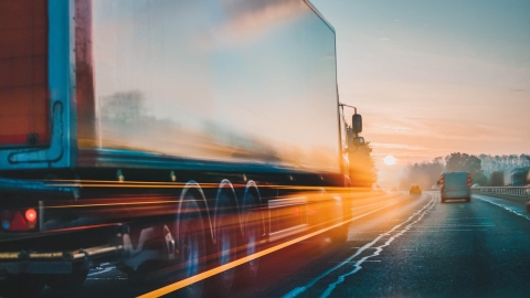 Semi-remorque roulant sur une autoroute en direction d'un coucher de soleil