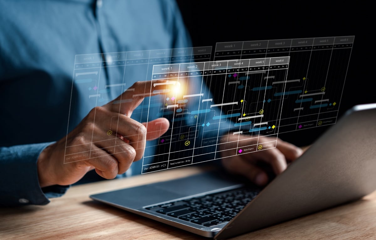 Redarea conceptuală a managementului flotei de camioane prin intermediul software-ului de monitorizare de la distanță care plutește în fața ecranului unui laptop în timp ce un manager de flotă interacționează cu programul