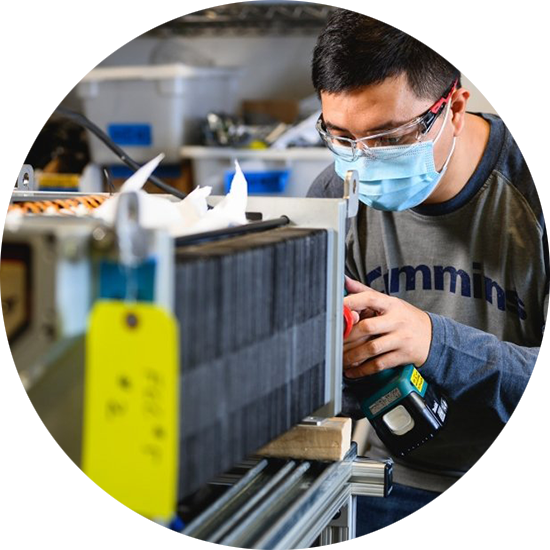 A man in safety equipment inspects a fuel cell.