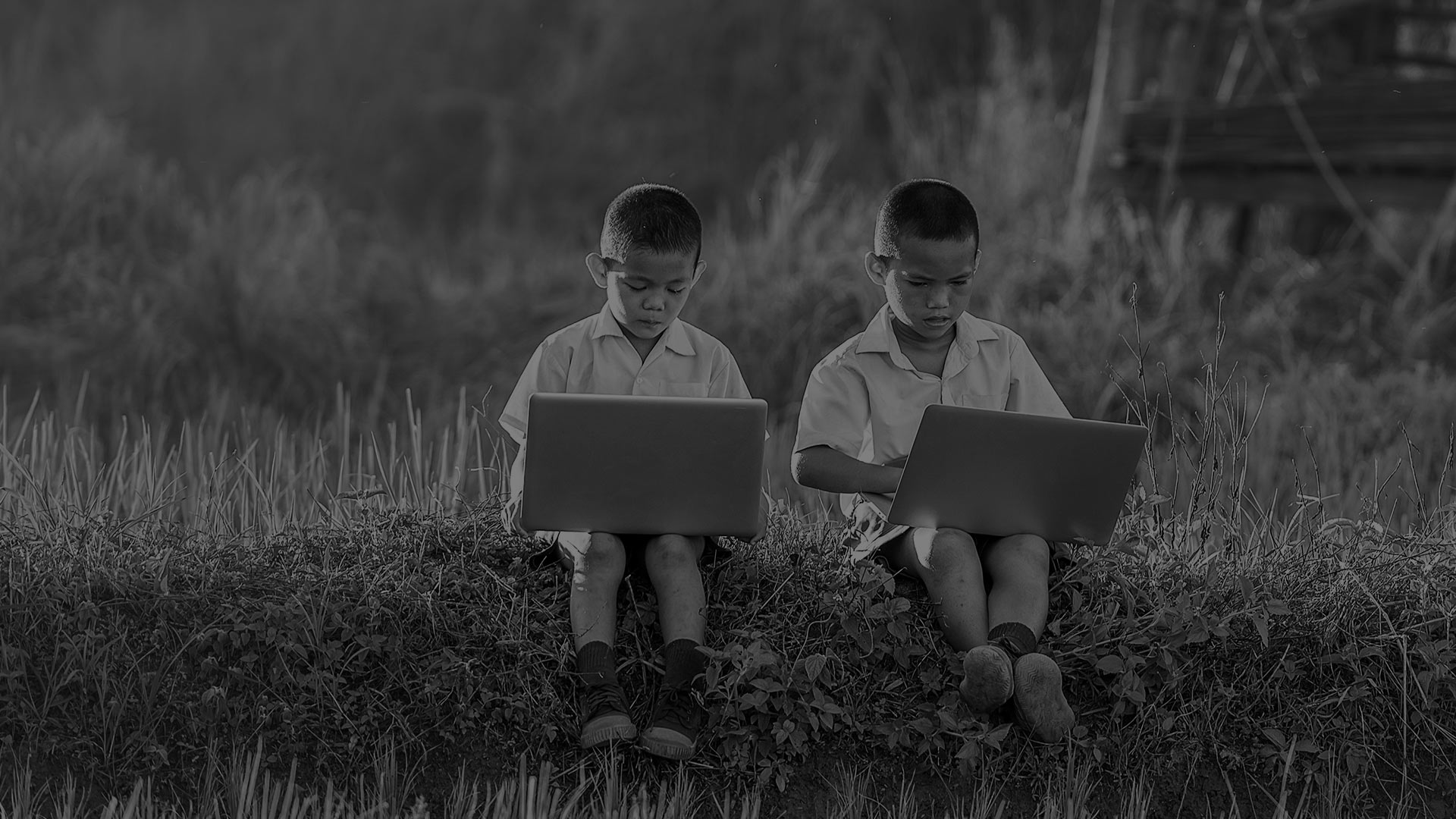 Here to help image - Two boys looking at their laptops.
