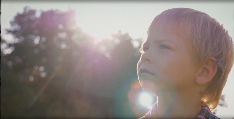 Imagine video miniaturală cu un băiețel în fața unui fundal însorit