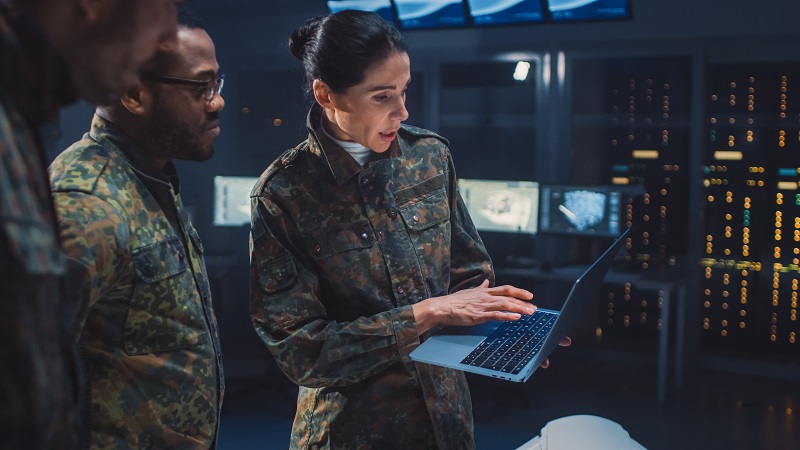 personale militare che si riunisce intorno a un laptop in un centro elaborazione dati
