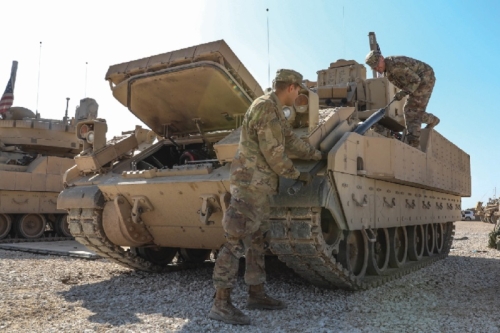 military personnel perform maintenance on a land tank