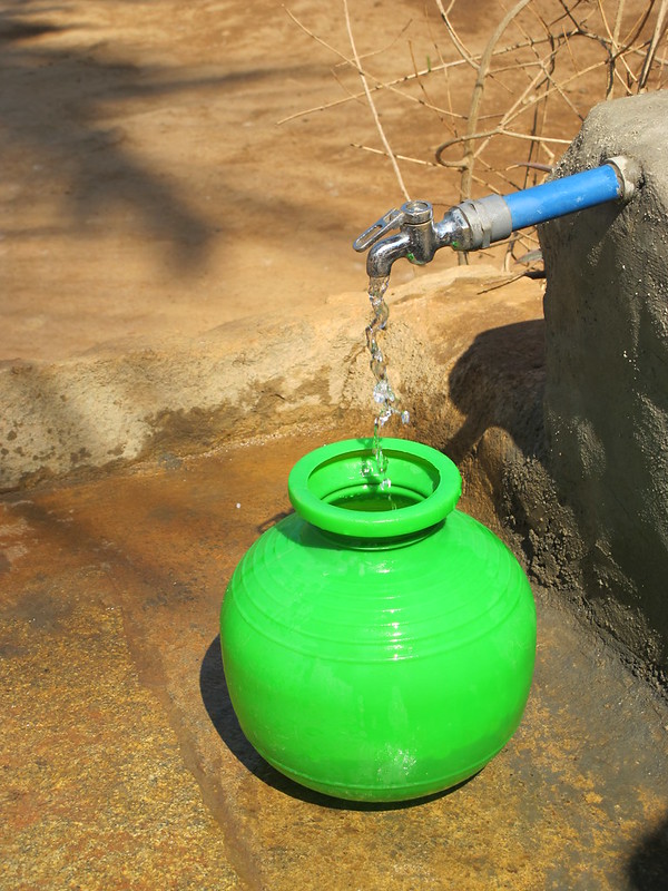 Nuevo grifo de agua que coloca agua en una olla verde