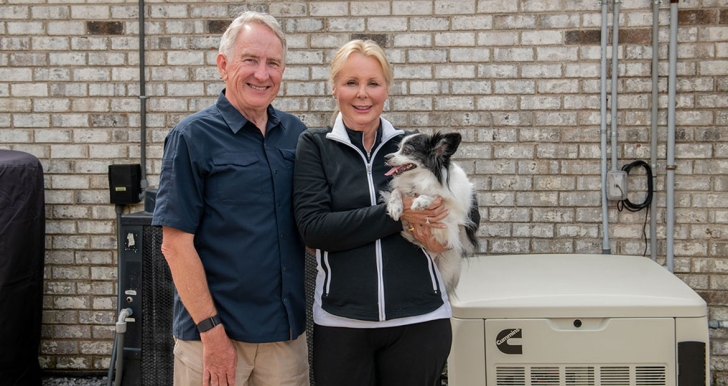 Una familia con un perro, de pie junto a un generador de energía de reserva para el hogar de Cummins