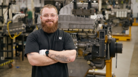Cummins tech in a production area with machinery in the background.