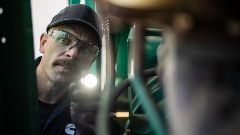 Cummins technician looking in dark area with a flashlight