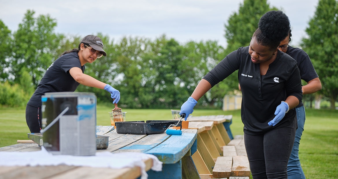 Employees painting a bench blue