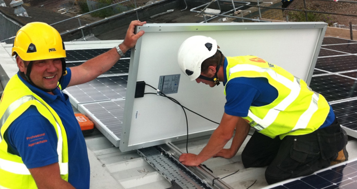workers wearing safety equipment install solar panels