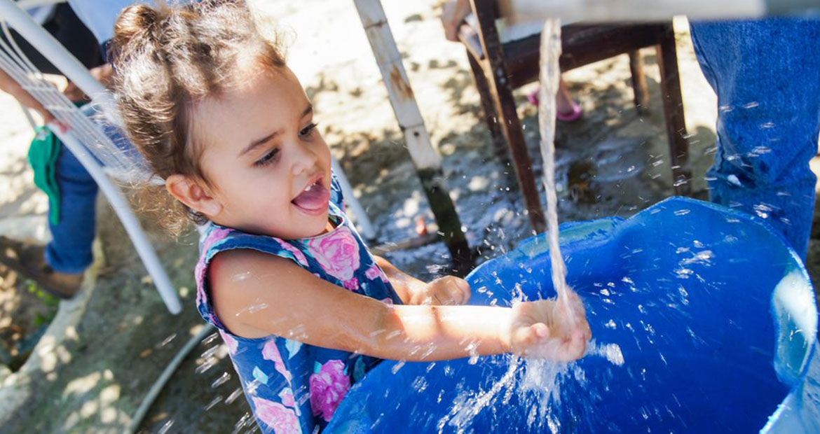 Child reaching hand out receiving clean water