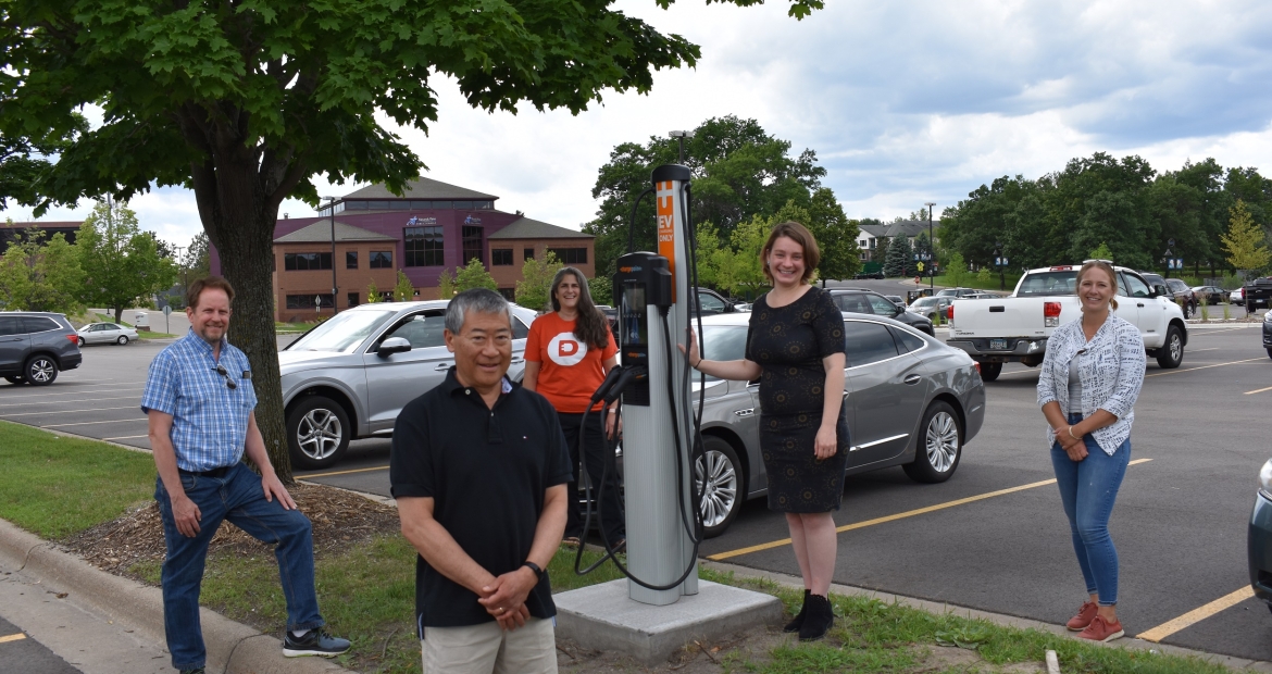 Team members gather around the new electric vehicle charging station developed in the city of Shoreview, Minnesota. Cummins employees contributed to the effort and are now working to create a charging station in the city of White Bear Lake (photo courtesy of the Great Plains Institute), Team members gather around the new electric vehicle charging station developed in the city of Shoreview, Minnesota. Cummins employees contributed to the effort and are now working to create a charging station in the city of White Bear Lake (photo courtesy of the Great Plains Institute).