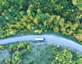 A semi truck driving on a winding road through the forest