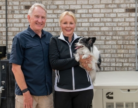 커민스 가정용 대기 발전기 옆에 서 있는 가족과 개