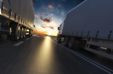 semi trucks powered by cummins on highway at sunset