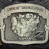 belt buckle with text reading "Cummins 300th QSK60 MCRS Upgrade"