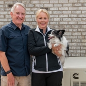 Una familia con un perro, de pie junto a un generador de energía de reserva para el hogar de Cummins