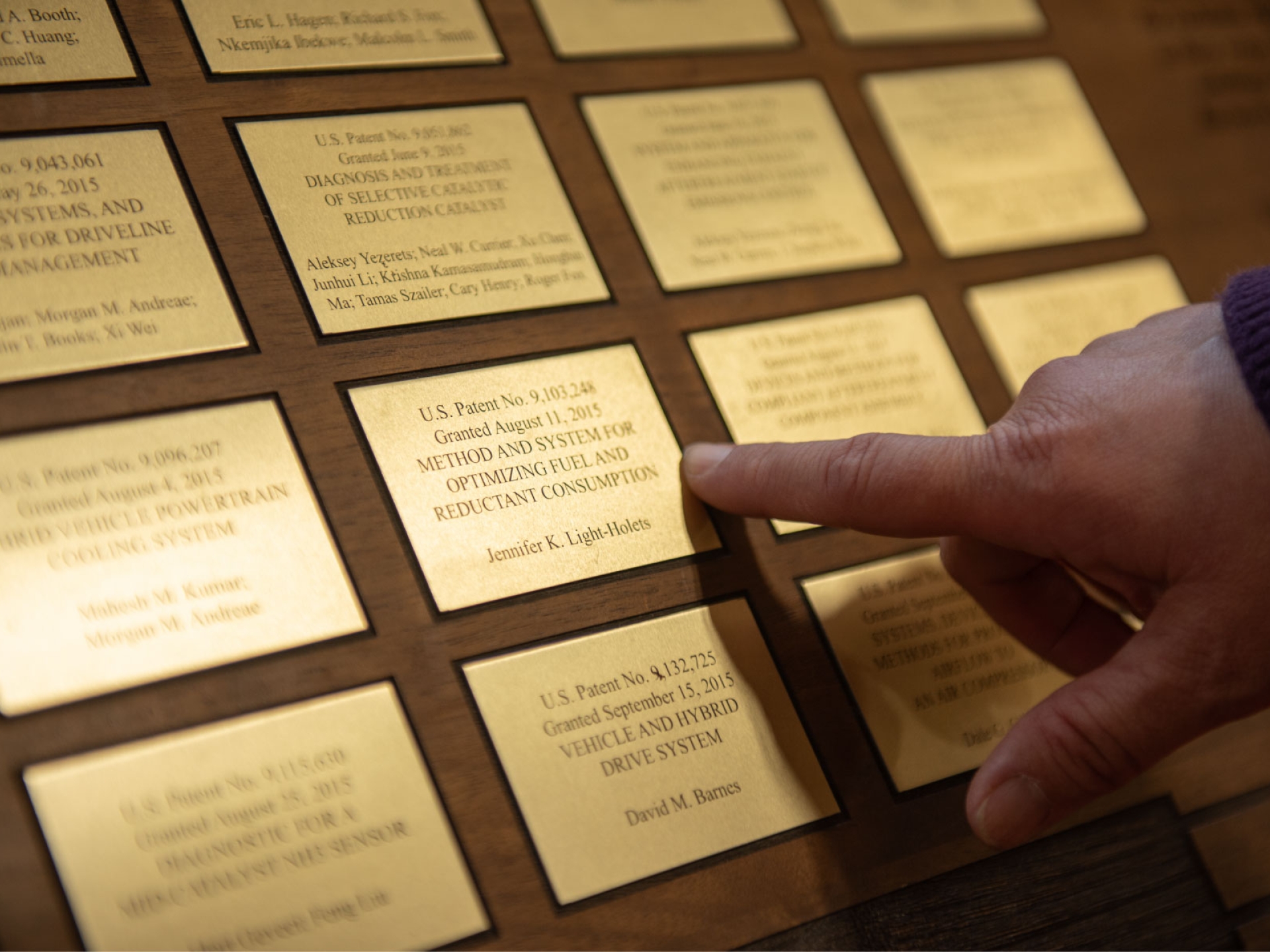 Jennifer, a Cummins engineer and inventor, points to her name on the Cummins patent wall