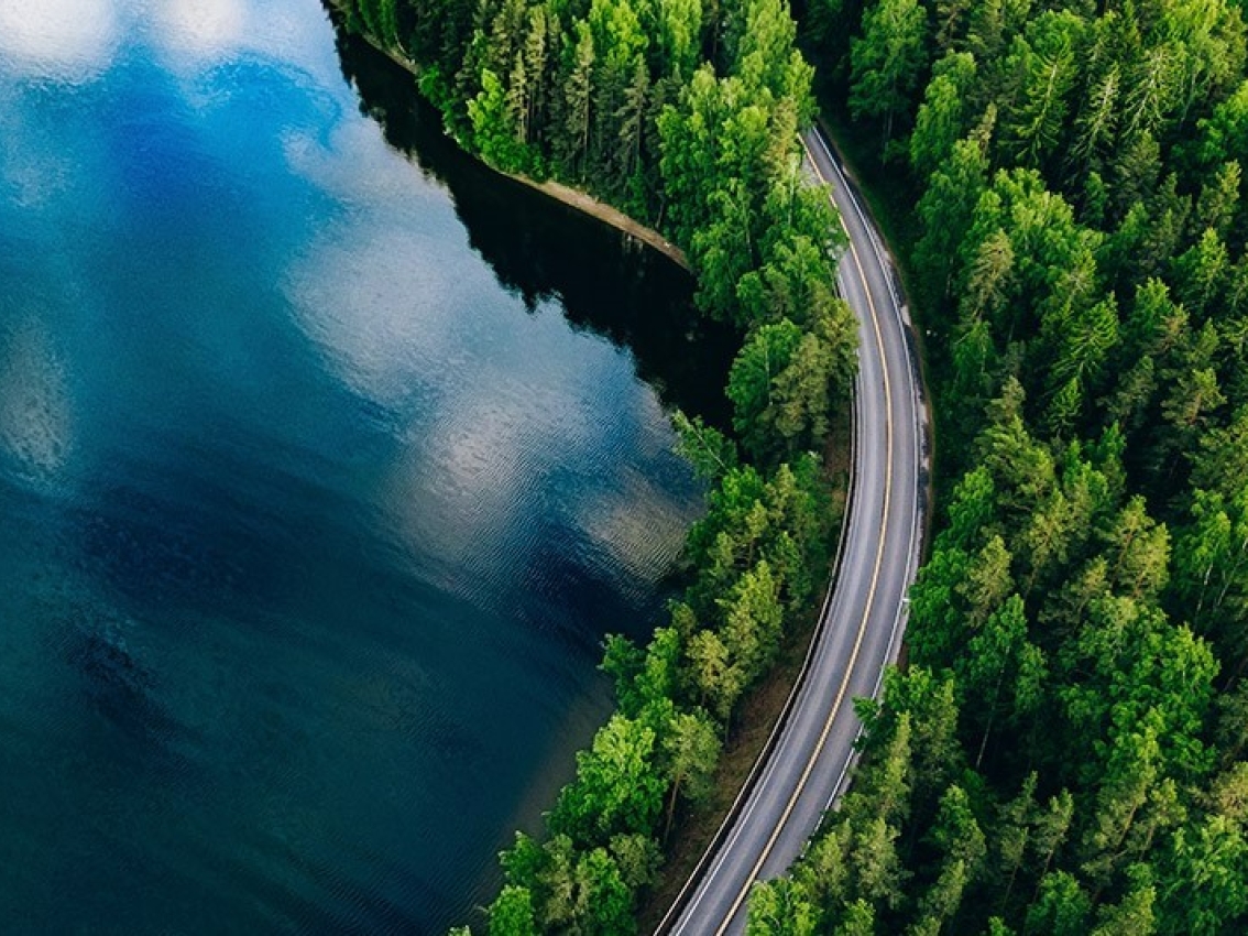 highway alongside forest and lake