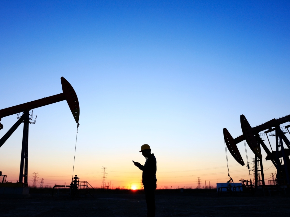 oil pump jacks with technician silhouette during low light